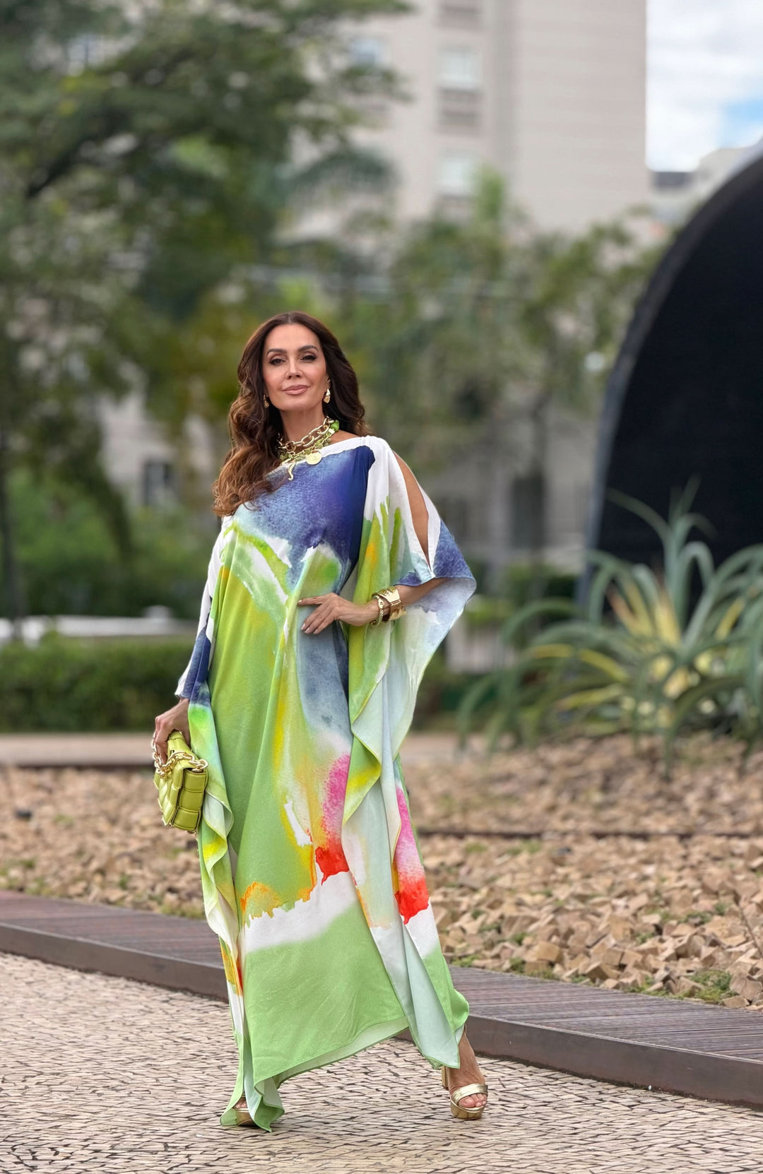 Mulher usando kaftan longo de seda com estampa aquarela colorida ao ar livre